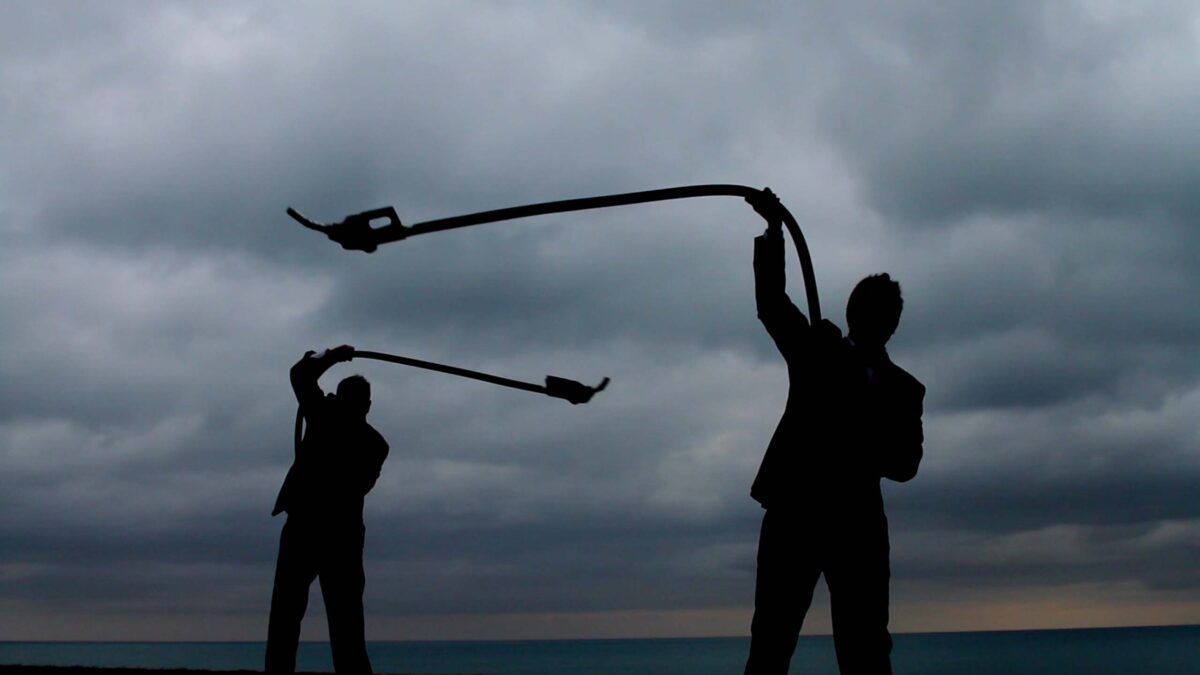 silhouette of two men swinging masks against a cloudy sky