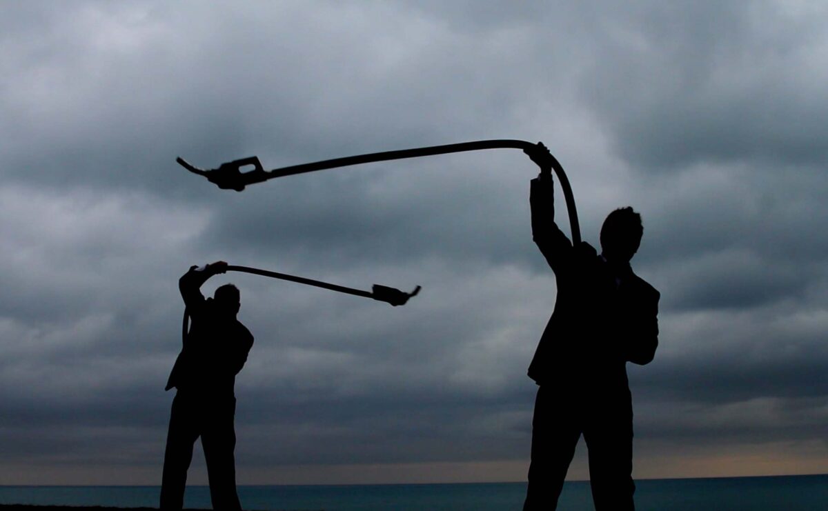 silhouette of two men swinging masks against a cloudy sky