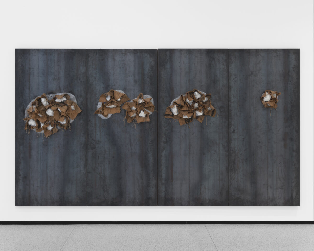 A black and grey canvas with brown, burlap circles protruding out of them.