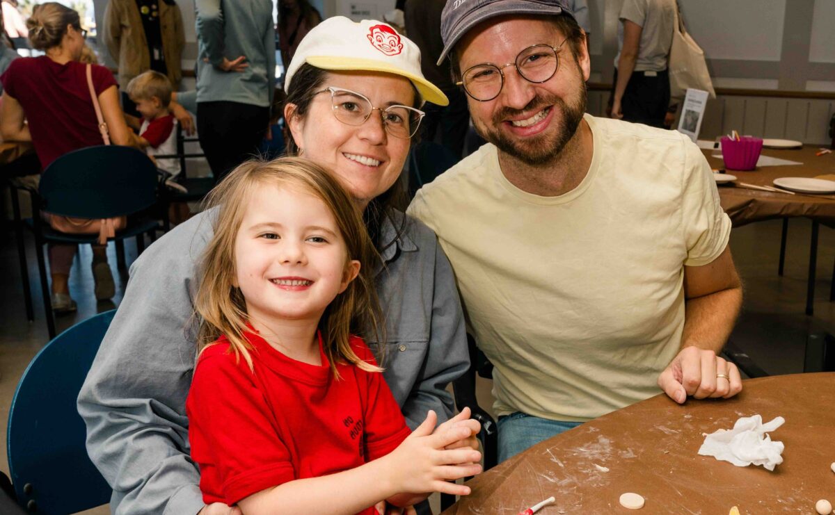 A family poses at a table with artmaking.