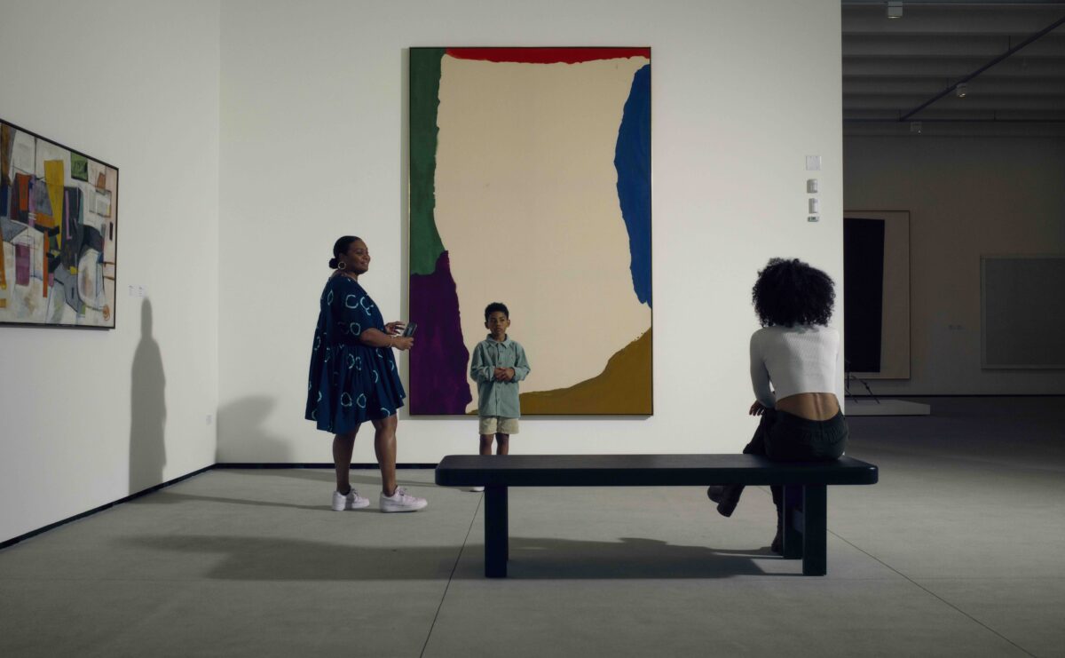 Three people in Foster Family Gallery, looking at a large canvas painting.