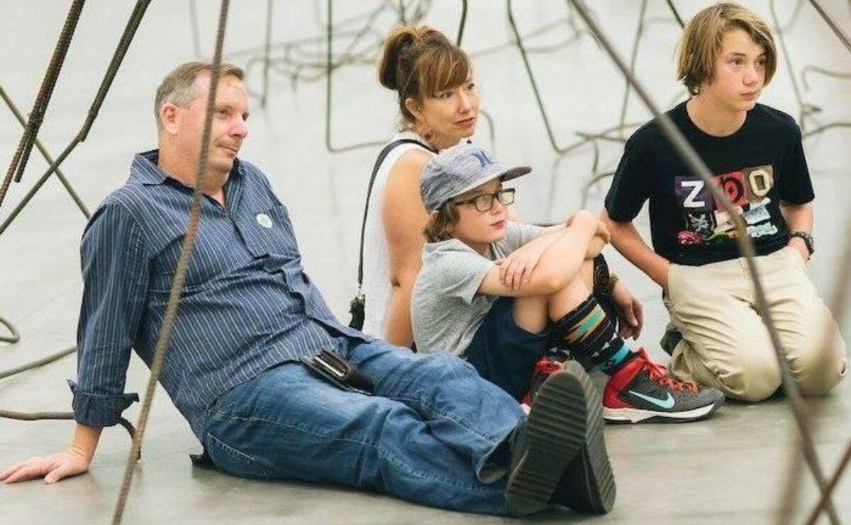 A family sitting on the ground experiencing art.