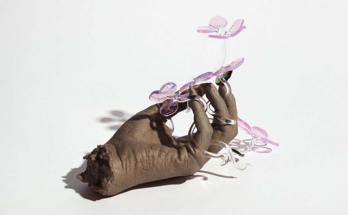 Flame-worked borosilicate glass in the form of flowers and lost-wax cast bronze in the form of a hand holding on to the flowers