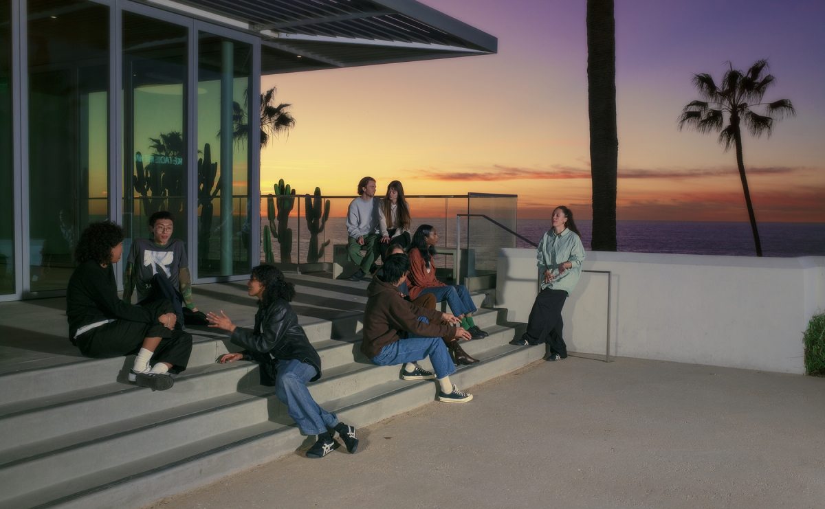 A group of people sitting on stairs outside as the sun sets
