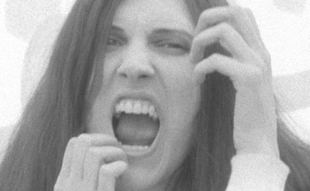 Black and white closeup of a woman with long brown hair screaming