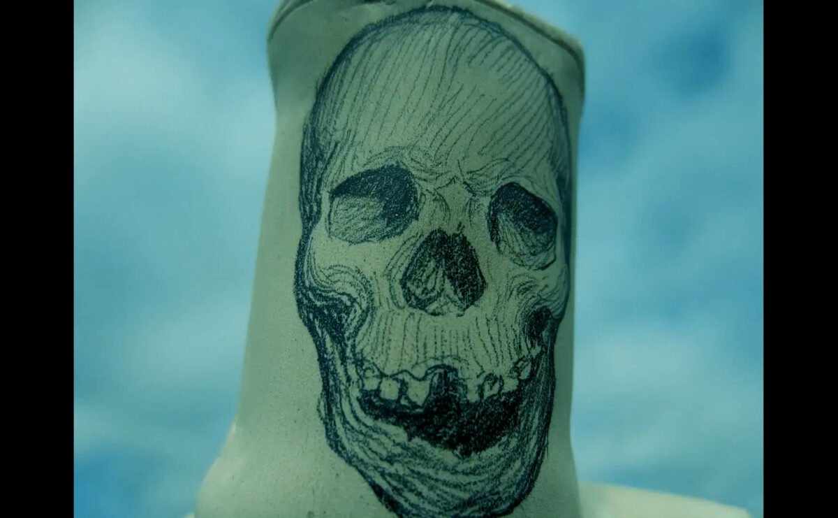 a skull hand drawn in black ink on a vase with a blue cloud background