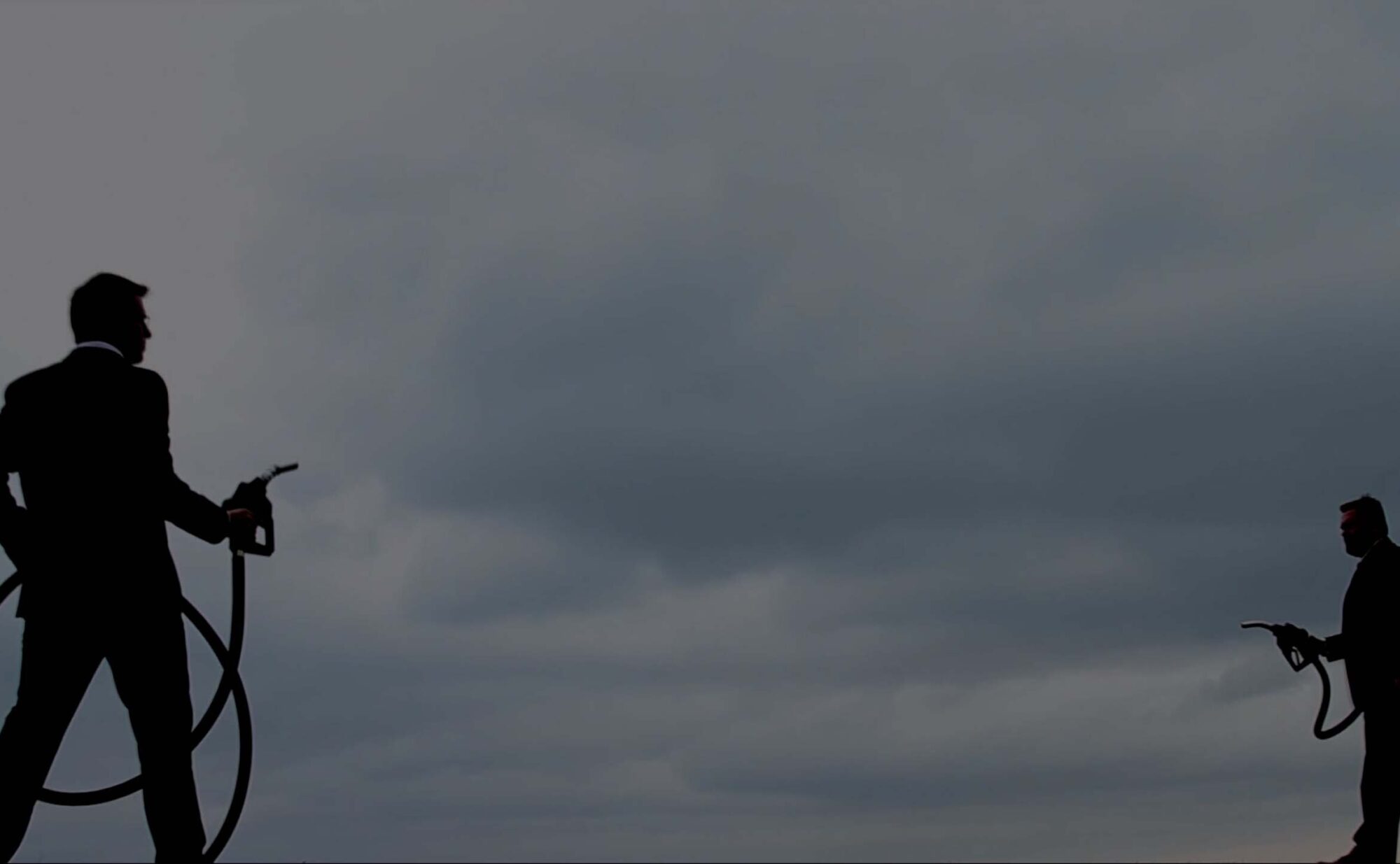 the silhouette of two people holding gas pumps.