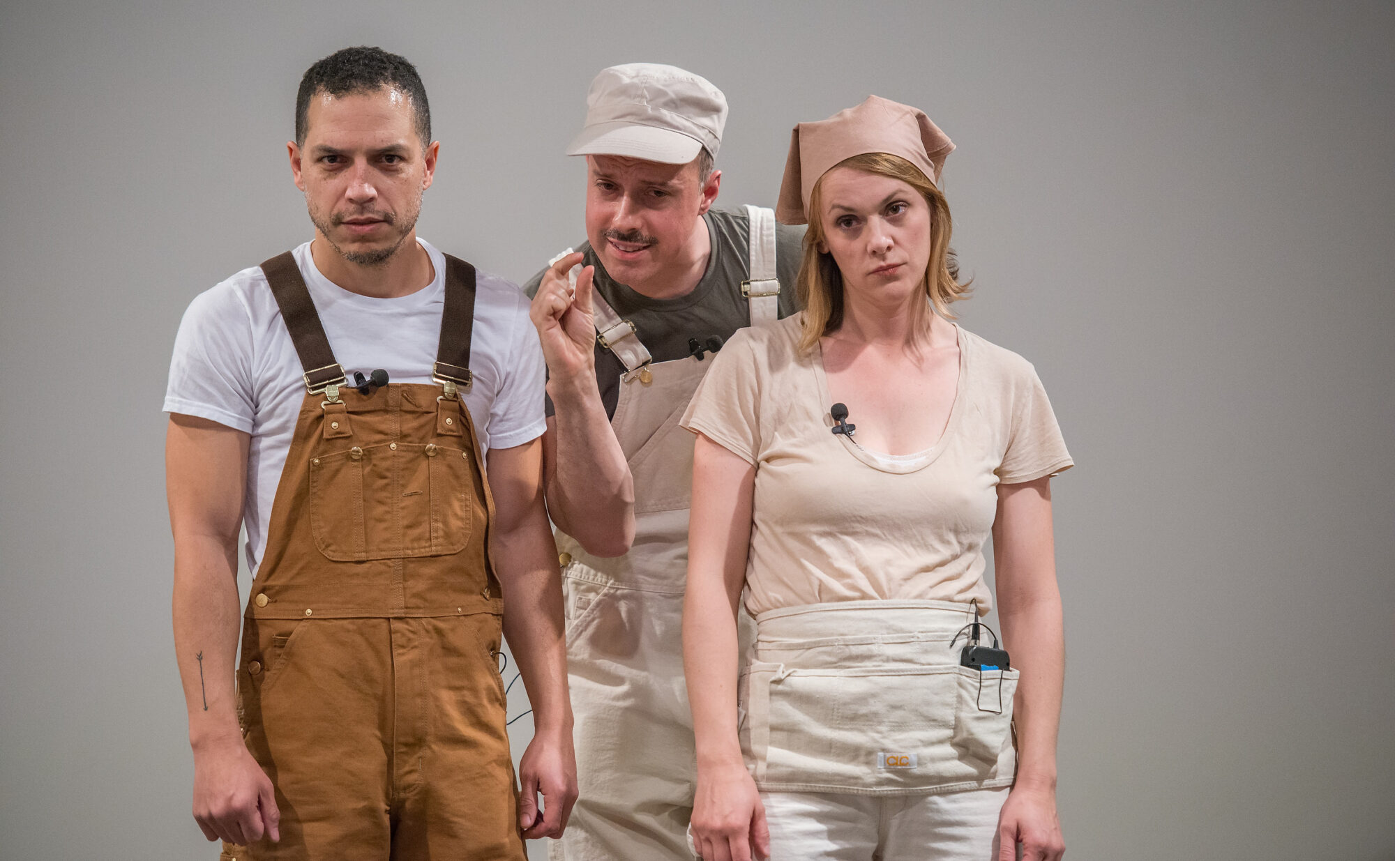 Three people that make up the collective My Barbarian are performing theatre against a silver background.