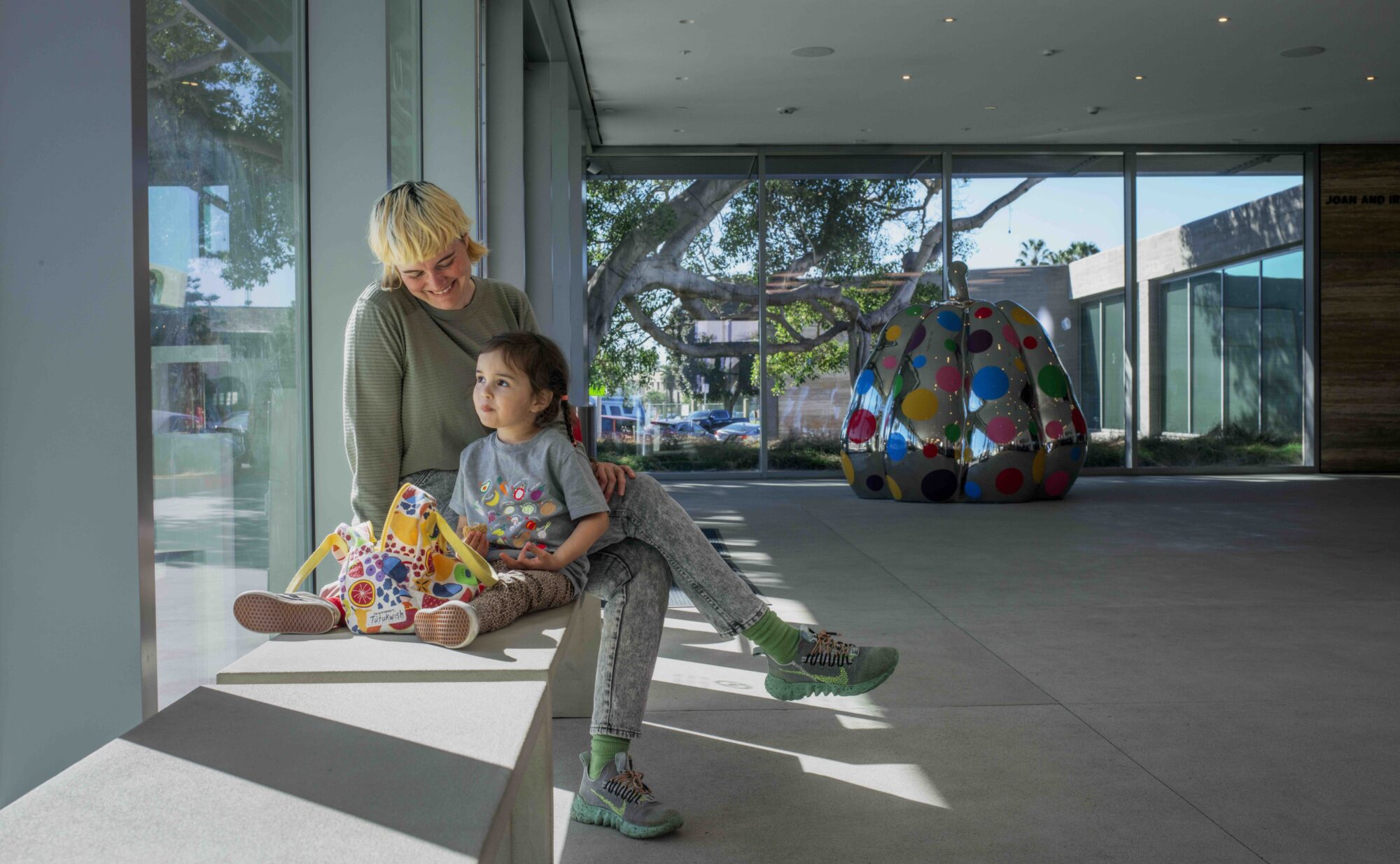 Caregiver looking down at young child with a warm smile with a large polka-dotted pumpkin in the background