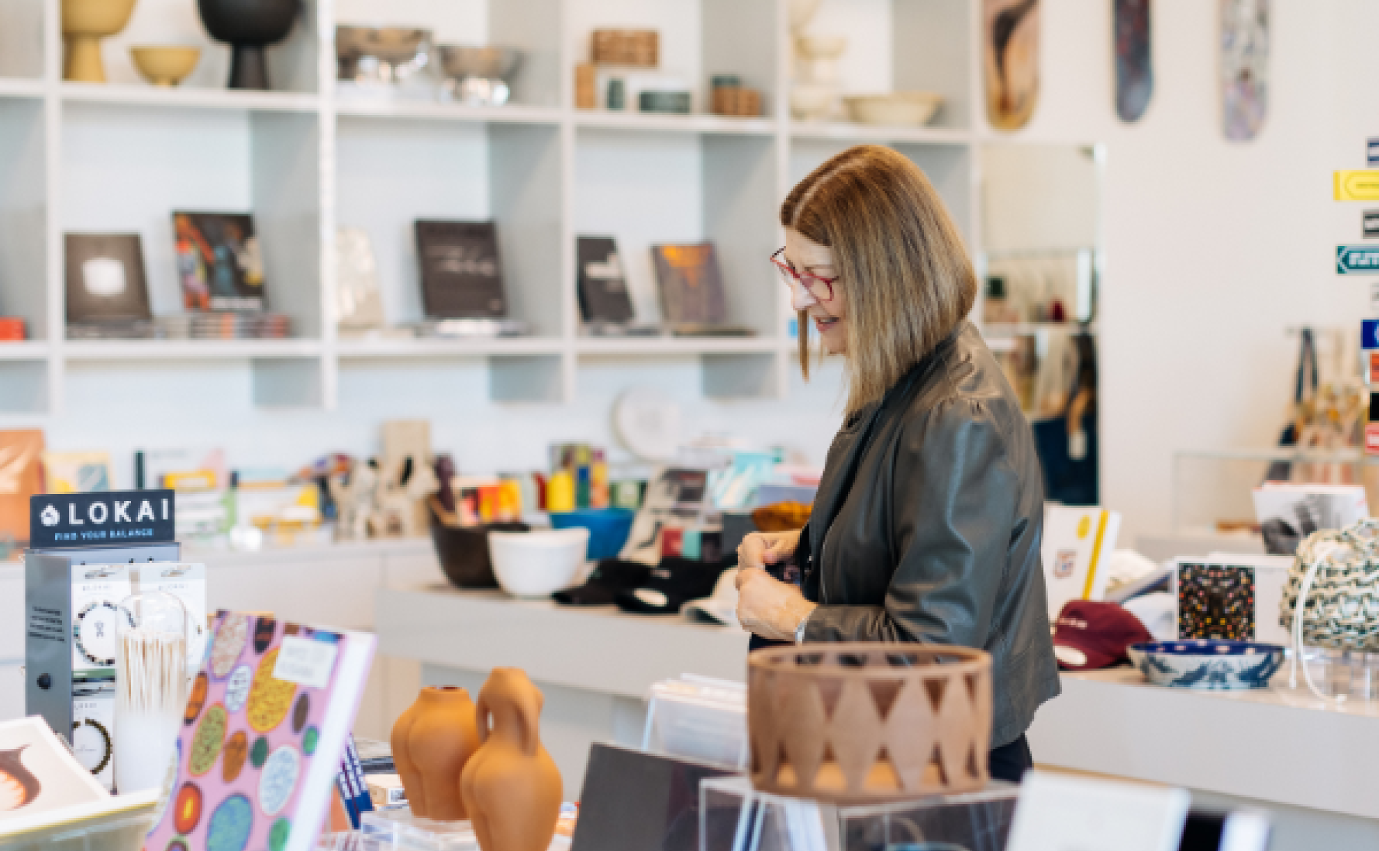 Woman wearing glasses walking by merchandise from The Shop