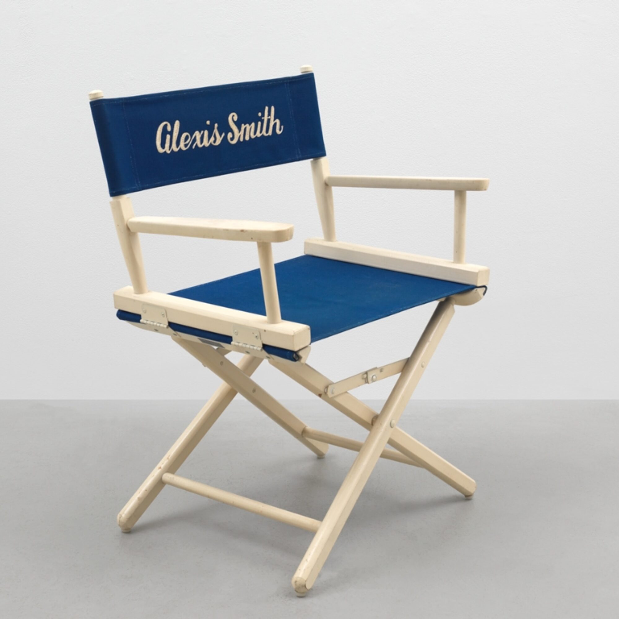 A directors chair with Alexis Smith printed on the blue fabric.