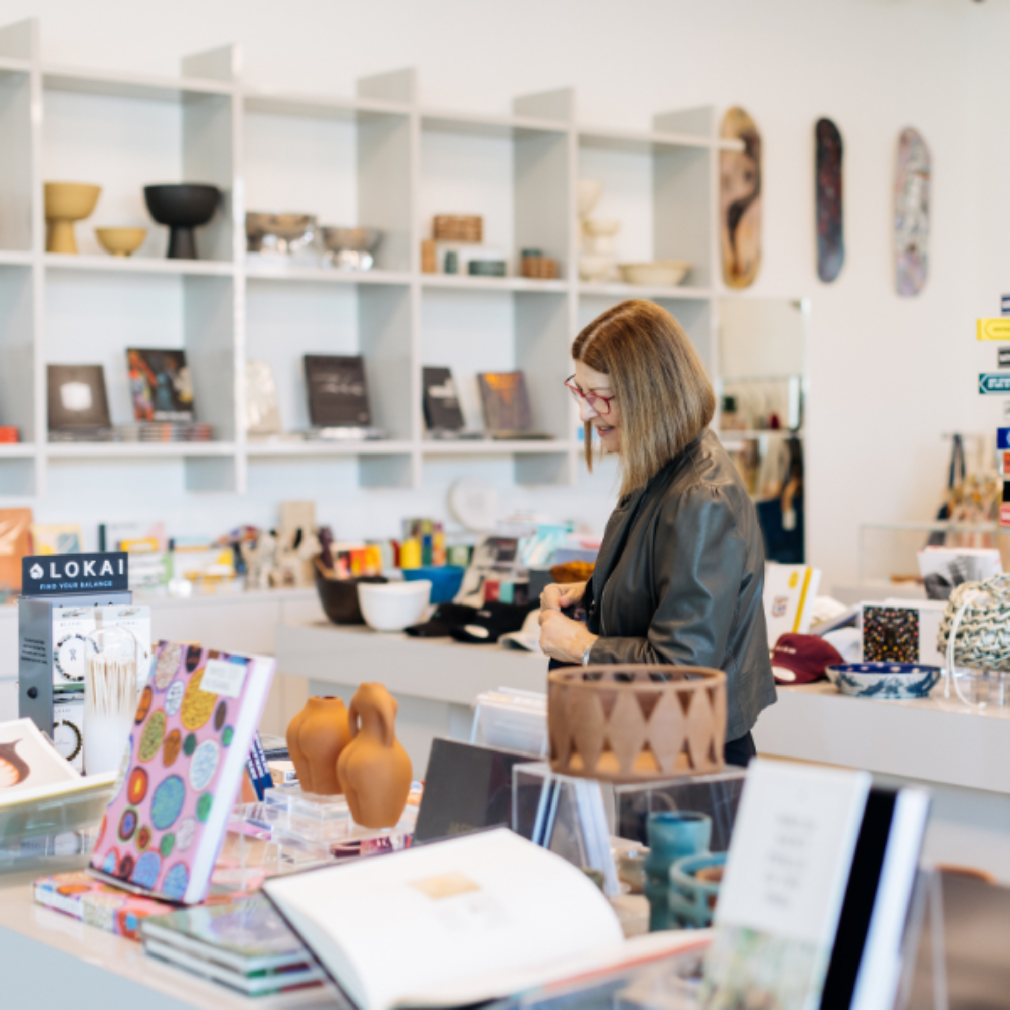 Woman wearing glasses walking by merchandise from The Shop