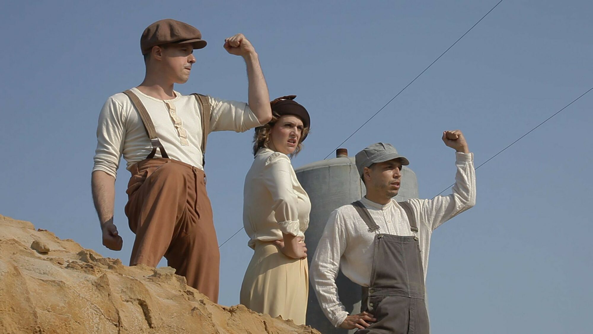 Still from video showing three people (two of them with their fists up)