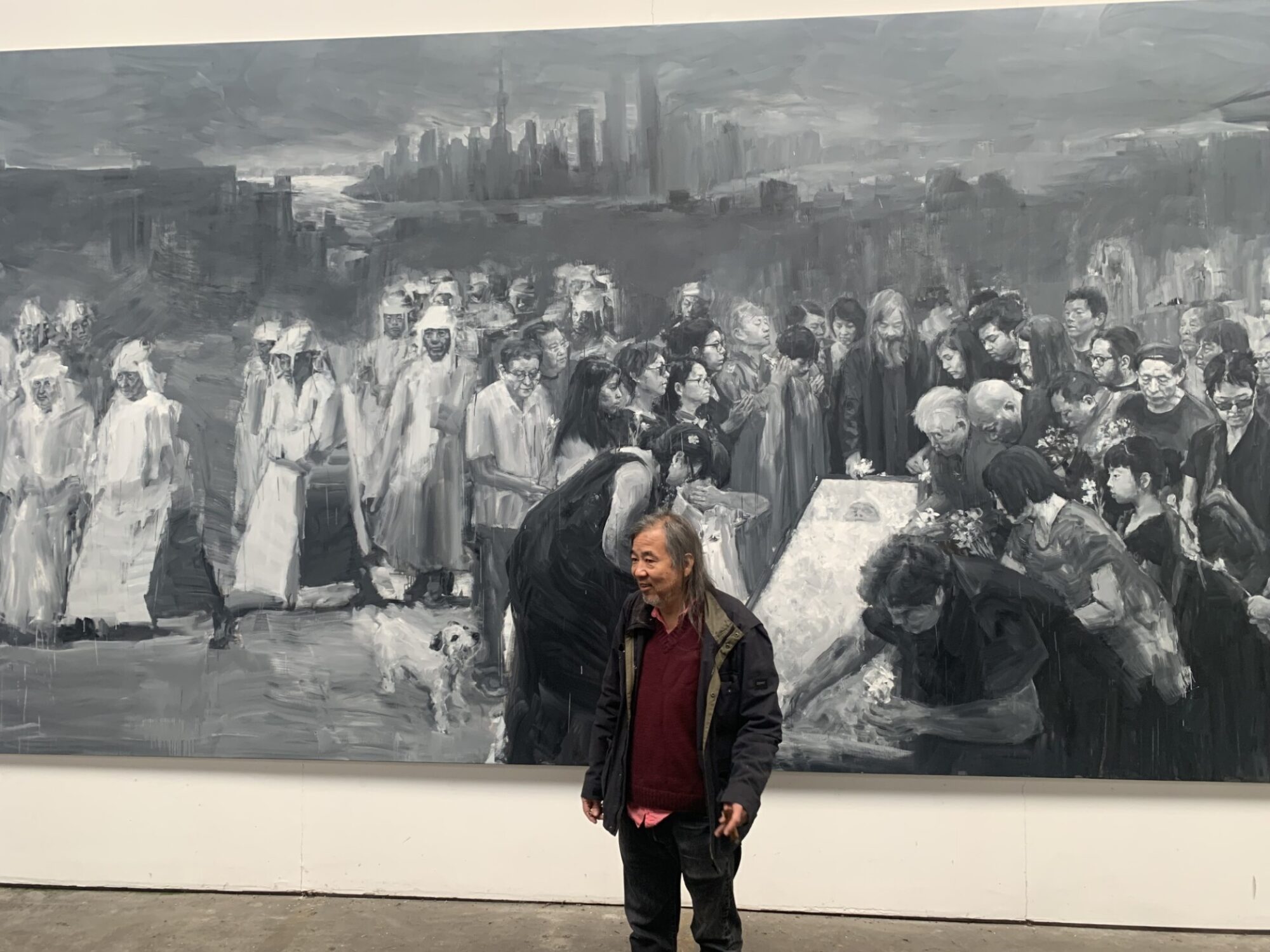 Yan Pei-Ming in front of their large canvas artwork.