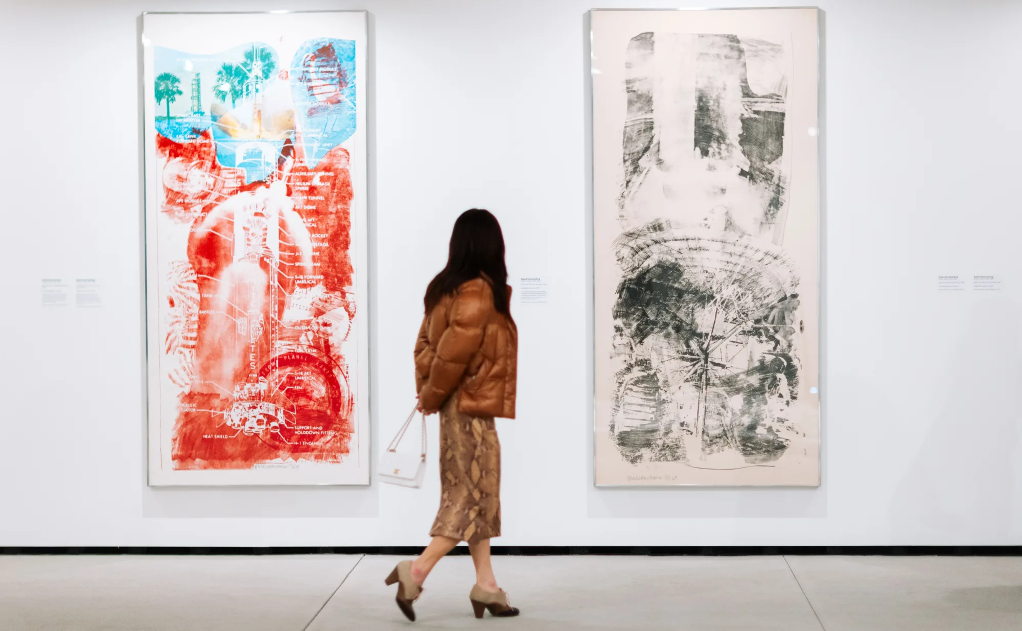 A person looking at two Rauschenburg artworks.